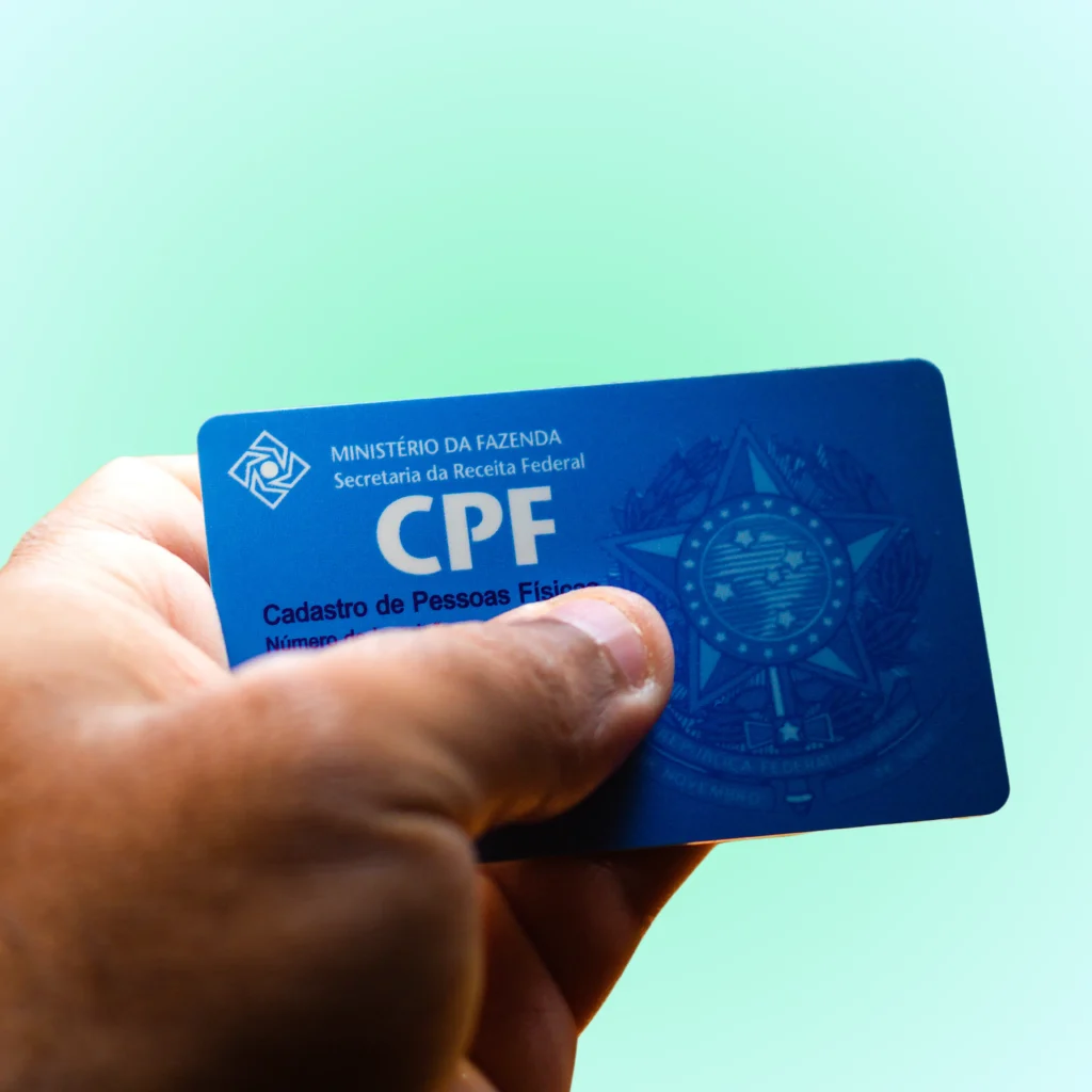 Pessoa segurando um cartão azul do CPF, representando o Cadastro de Pessoas Físicas no Brasil.